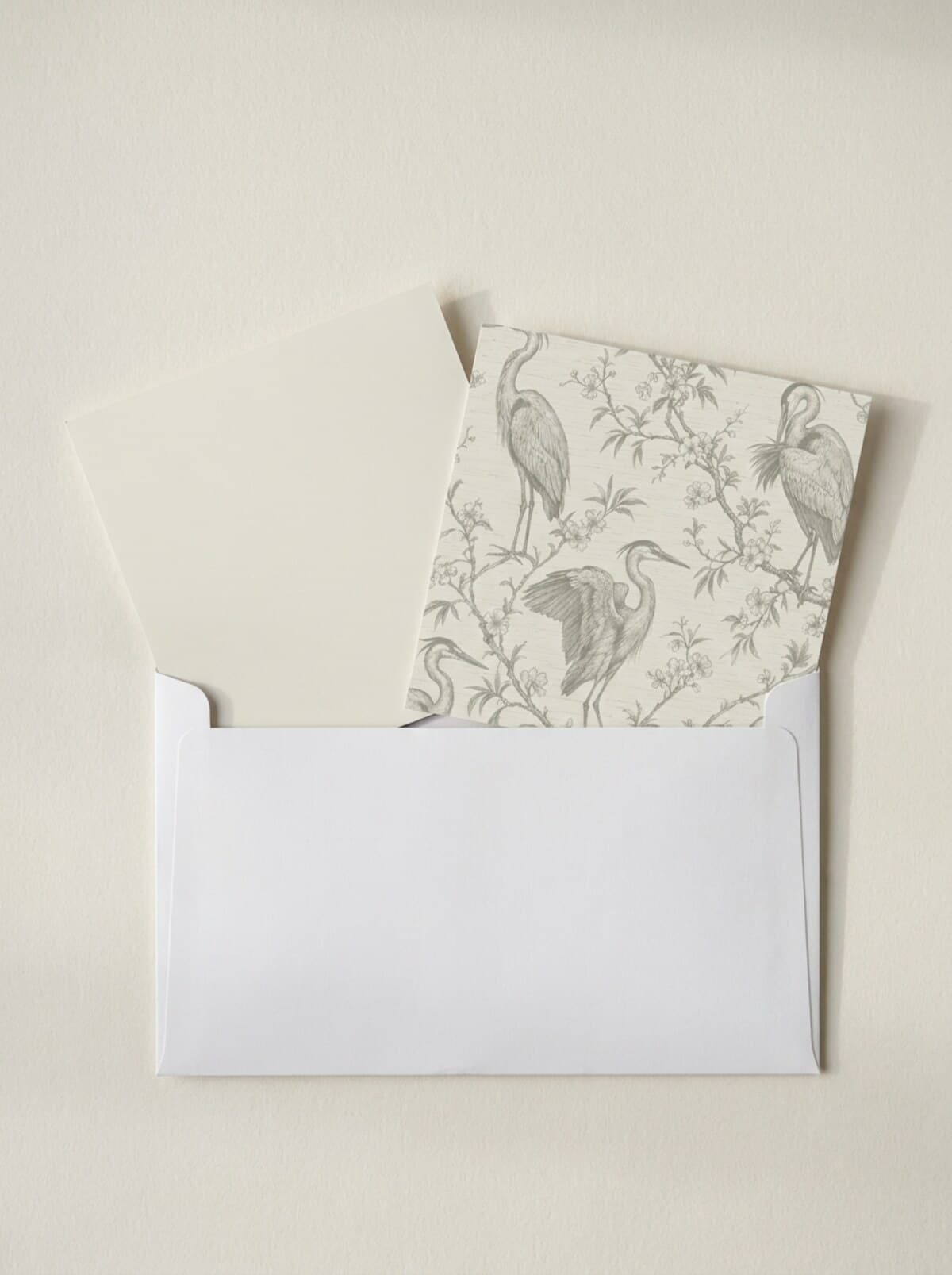 A white envelope with two square samples half out of it, one a plain paint color and one the same color printed with Heron and Sprig